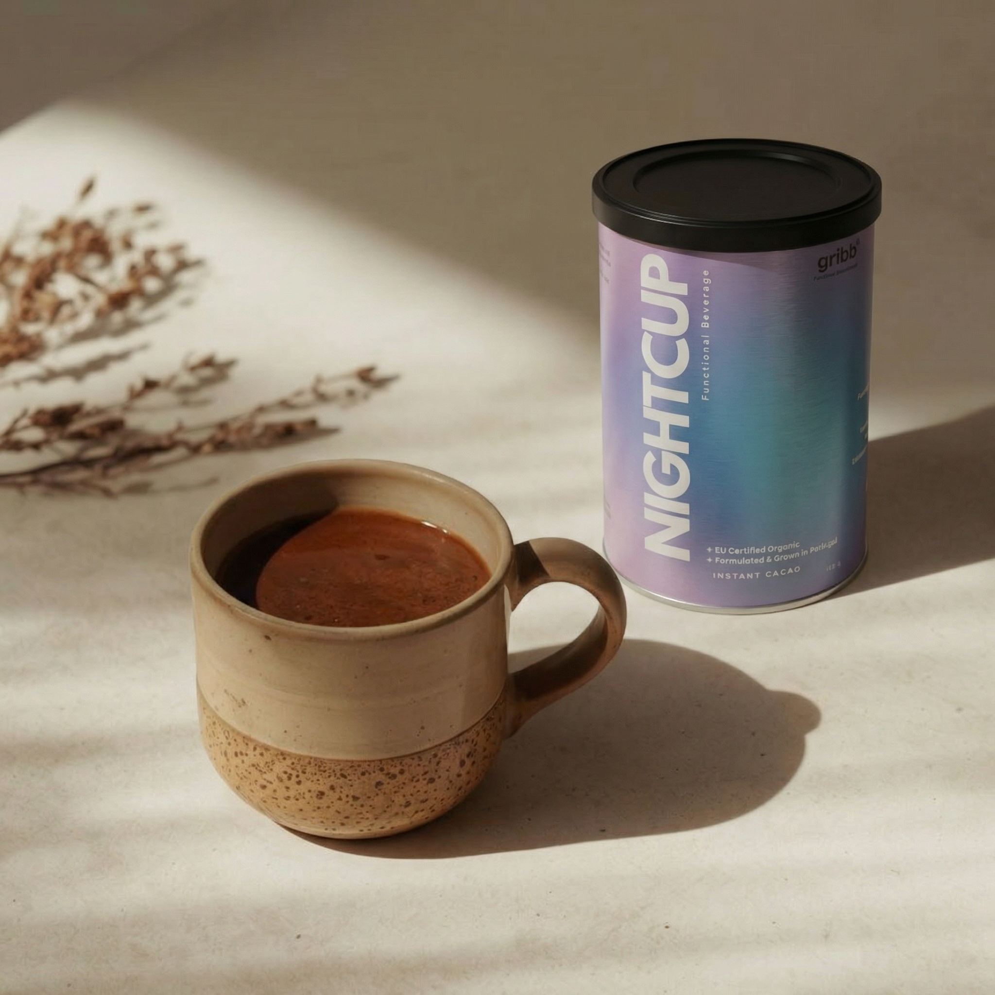 Ceramic mug with coffee and a can of 'Nightcup' coffee on a neutral background