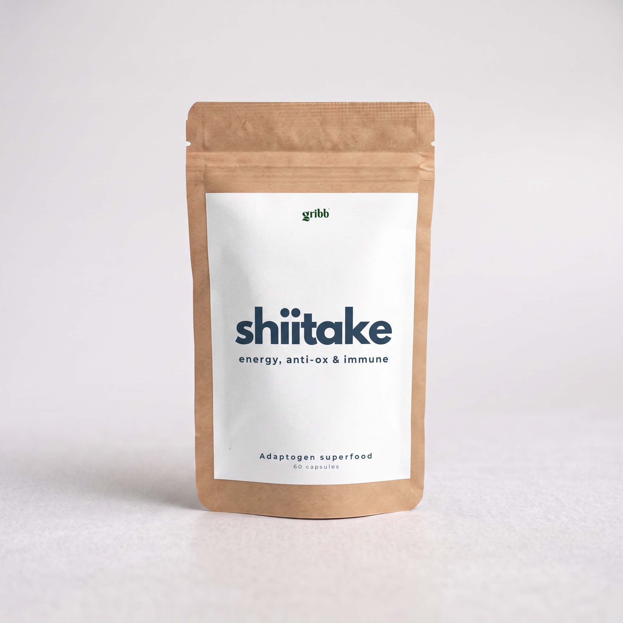 A kraft paper stand-up pouch of Gribb Shiitake adaptogen superfood with a white label, photographed on a light gray background.